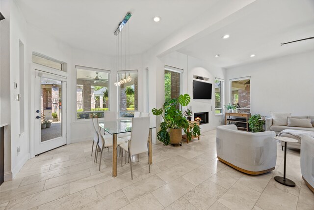 interior space with recessed lighting, a wealth of natural light, a ceiling fan, and a lit fireplace