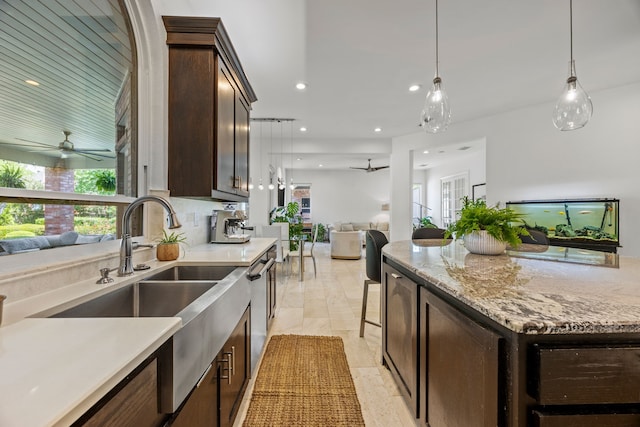 kitchen with ceiling fan, dark brown cabinetry, open floor plan, and a healthy amount of sunlight
