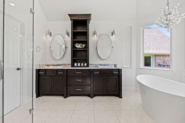 full bath featuring a sink, a chandelier, double vanity, a freestanding bath, and baseboards