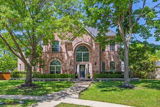 traditional-style home featuring brick siding and a front lawn