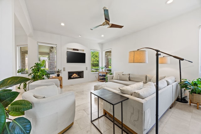 living area featuring recessed lighting, a ceiling fan, and a lit fireplace