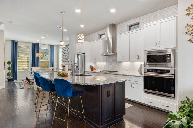 1023 Tea Olive Ln, Dallas, TX 75212 - kitchen with stainless steel appliances, wall chimney exhaust hood, a center island with sink, backsplash, and dark wood finished floors