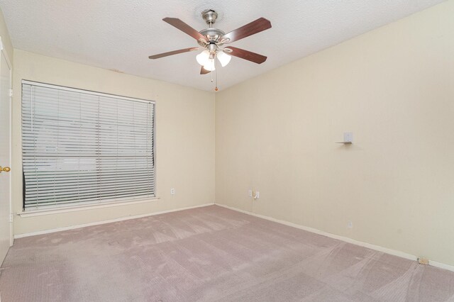 unfurnished room with light colored carpet, a ceiling fan, baseboards, and a textured ceiling
