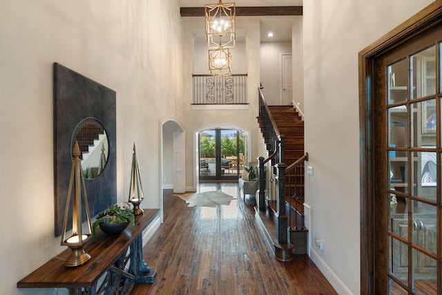 entrance foyer with arched walkways, stairway, hardwood / wood-style flooring, and baseboards