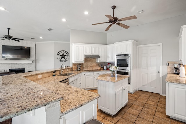 kitchen featuring double oven, backsplash, a ceiling fan, and a sink