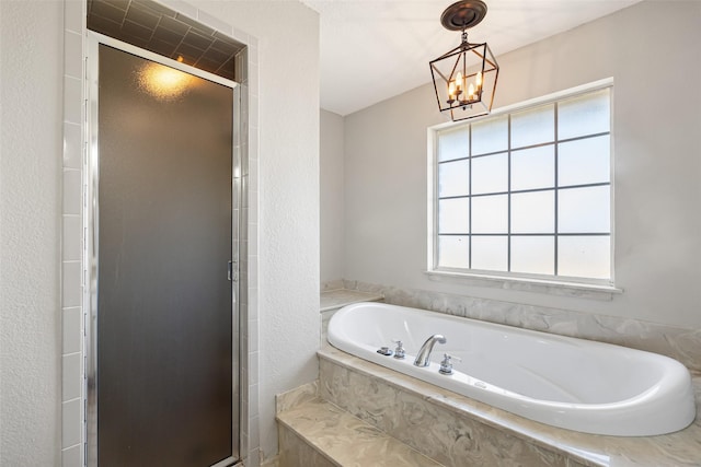 bathroom featuring a bath, an inviting chandelier, and a stall shower