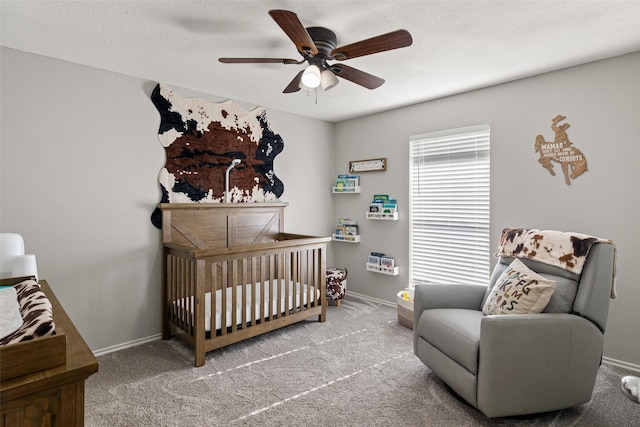 bedroom with baseboards, a ceiling fan, a crib, and carpet