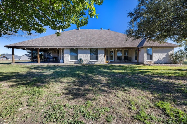 rear view of property featuring a lawn, brick siding, and a patio