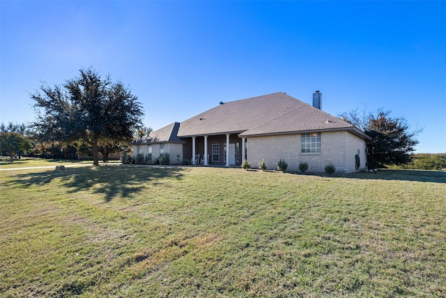 view of front of home featuring a chimney, brick siding, and a front lawn