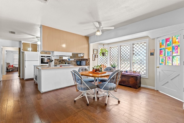 dining room with hardwood / wood-style floors, a textured ceiling, a ceiling fan, and visible vents