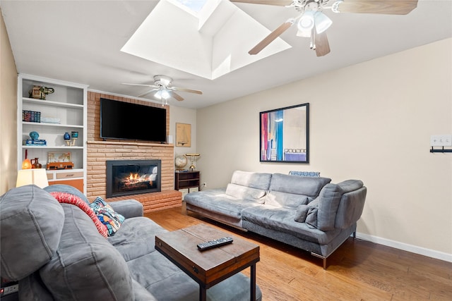 living area with baseboards, a ceiling fan, wood finished floors, and a skylight