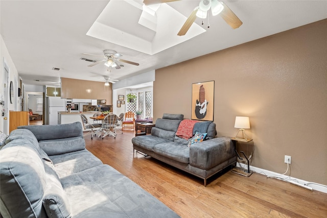 living area with ceiling fan, light wood-style floors, visible vents, and a skylight