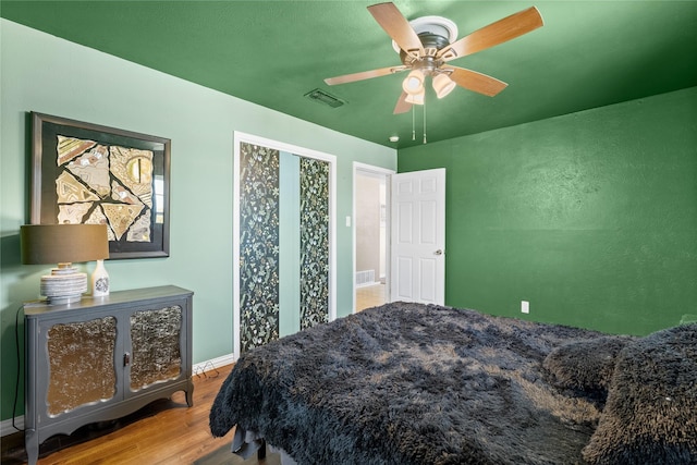 bedroom with wood finished floors, visible vents, baseboards, and ceiling fan