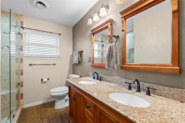 bathroom featuring a shower stall, wood finished floors, toilet, and a sink