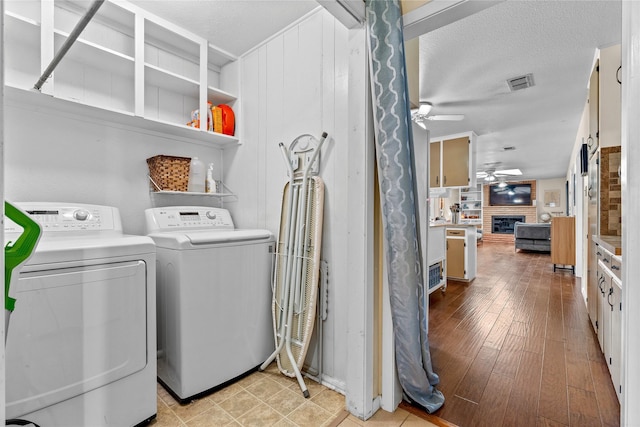 washroom featuring washing machine and clothes dryer, visible vents, ceiling fan, a fireplace, and laundry area
