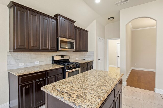 248 Van Buren Dr, Forney, TX 75126 - kitchen with appliances with stainless steel finishes, arched walkways, backsplash, light stone countertops, and baseboards