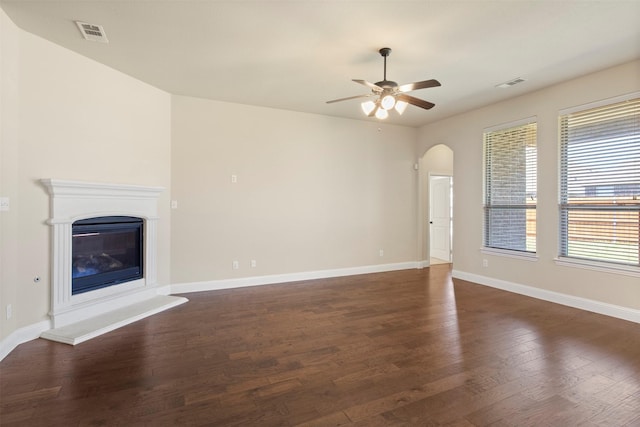 248 Van Buren Dr, Forney, TX 75126 - unfurnished living room with a ceiling fan, wood finished floors, baseboards, a glass covered fireplace, and arched walkways