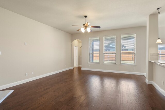 248 Van Buren Dr, Forney, TX 75126 - unfurnished living room featuring ceiling fan, dark wood finished floors, arched walkways, and baseboards