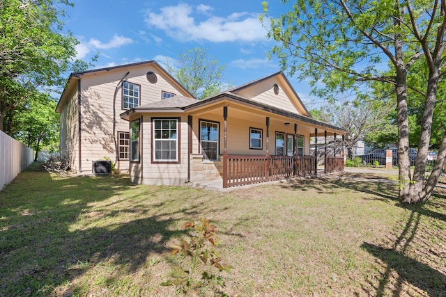 farmhouse featuring a front lawn, fence, central AC unit, and covered porch