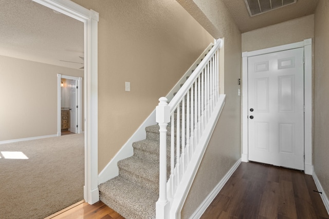stairway with baseboards, wood finished floors, and visible vents