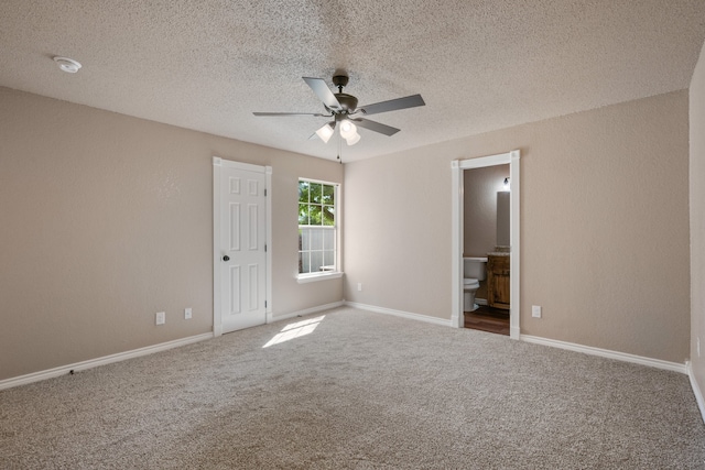unfurnished bedroom with a ceiling fan, carpet floors, ensuite bath, baseboards, and a textured ceiling