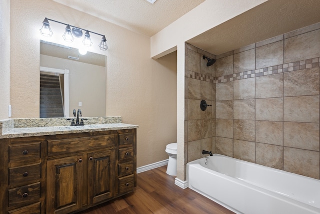 full bathroom with wood finished floors, toilet, vanity,  shower combination, and a textured ceiling