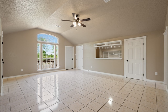 empty room with lofted ceiling, visible vents, a ceiling fan, light tile patterned floors, and a textured ceiling