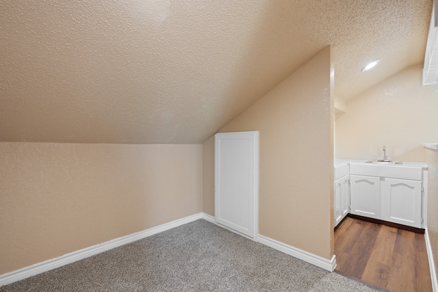 bonus room with vaulted ceiling, a textured ceiling, baseboards, and a sink