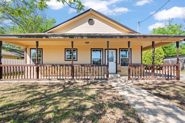 farmhouse inspired home with fence and covered porch