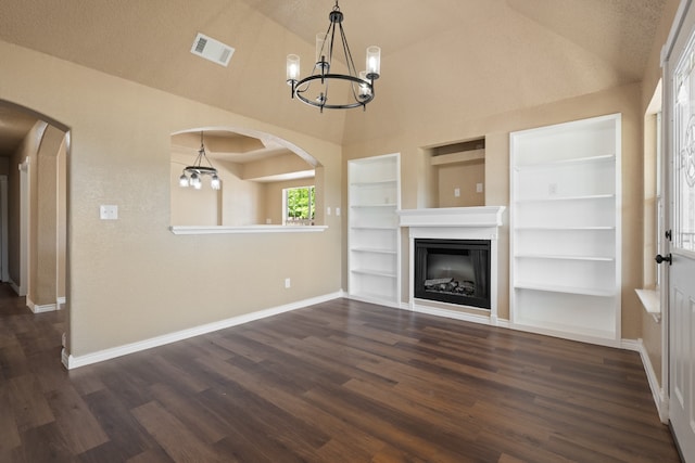 unfurnished living room featuring built in shelves, arched walkways, and a chandelier