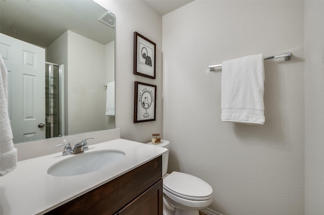 bathroom featuring toilet, visible vents, vanity, and a stall shower