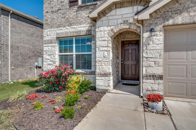 doorway to property with a garage and stone siding
