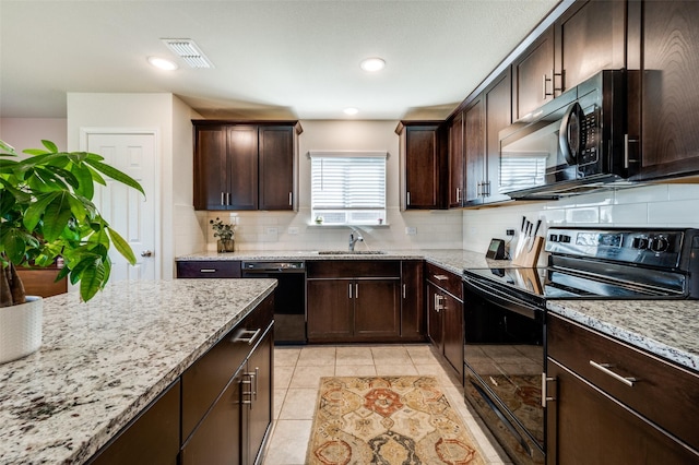 kitchen with light stone counters, tasteful backsplash, a sink, black appliances, and visible vents