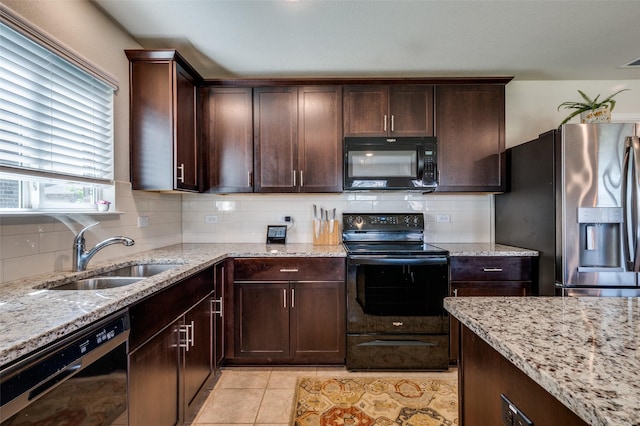 kitchen featuring a sink, dark brown cabinets, backsplash, light stone counters, and black appliances