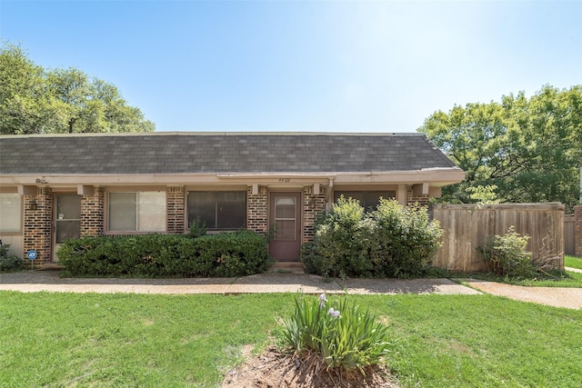 ranch-style house featuring brick siding, a shingled roof, and a front yard