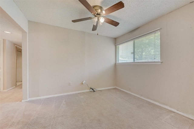 carpeted spare room featuring baseboards, a textured ceiling, and ceiling fan