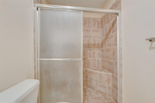 full bath featuring a shower stall and toilet
