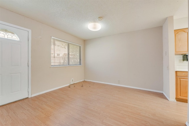 entryway with baseboards, a textured ceiling, and light wood-style flooring