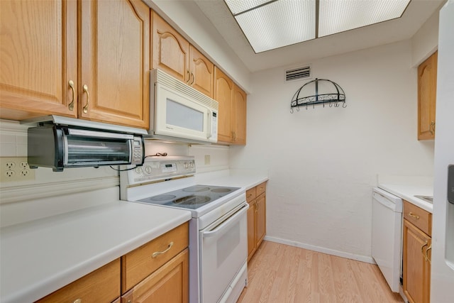 kitchen with white appliances, light wood finished floors, light countertops, baseboards, and visible vents
