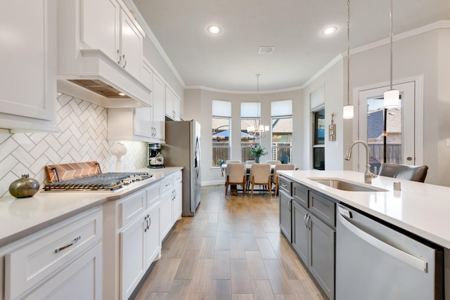 kitchen with crown molding, a sink, gray cabinets, light countertops, and appliances with stainless steel finishes