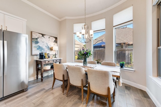 dining room featuring light wood-style floors, ornamental molding, baseboards, and a notable chandelier