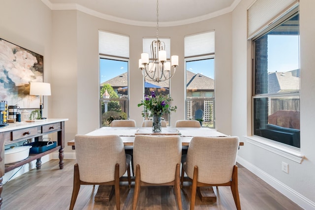 dining space featuring ornamental molding, a notable chandelier, and wood finished floors