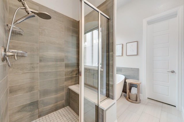 full bathroom with a shower stall, a freestanding bath, and tile patterned flooring