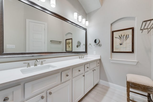 bathroom featuring baseboards, a sink, and double vanity