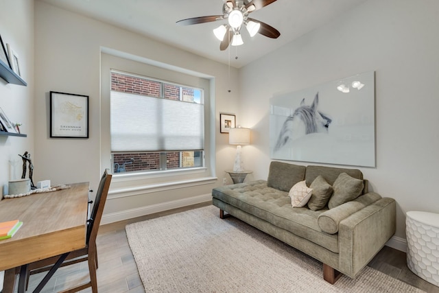 living area featuring wood finished floors, baseboards, and ceiling fan