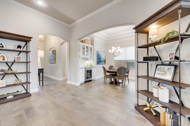 dining room with wine cooler, arched walkways, baseboards, a notable chandelier, and ornamental molding