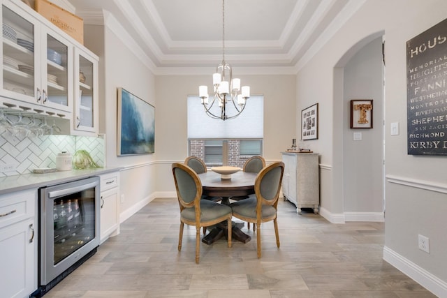 dining room with light wood-style floors, arched walkways, a raised ceiling, a notable chandelier, and wine cooler
