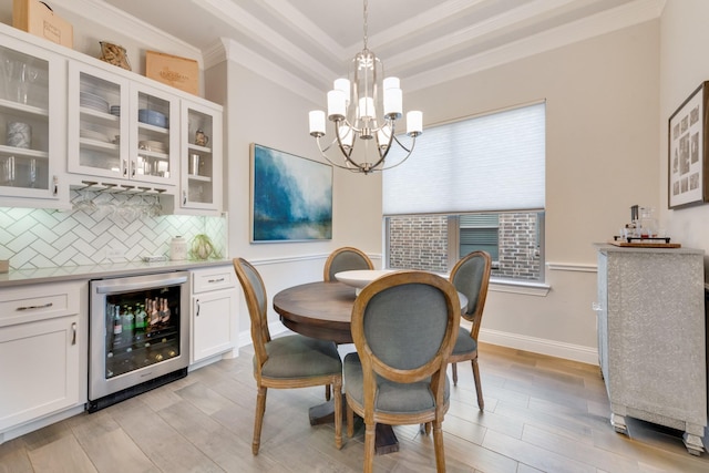 dining space with an inviting chandelier, crown molding, beverage cooler, and light wood-style flooring