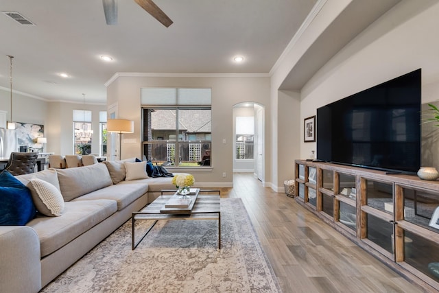 living room with wood finished floors, visible vents, arched walkways, baseboards, and ceiling fan with notable chandelier