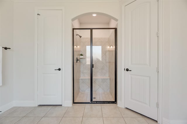 interior space featuring baseboards, arched walkways, and light tile patterned floors